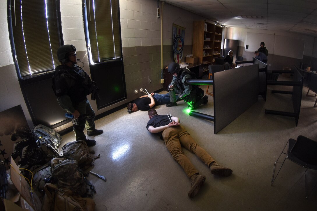 Civilian police and cadets apprehend role-playing aggressors.