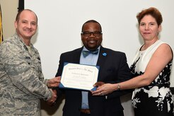 Dr. Norris Williams, Sumter School District leadership and school excellence assistant superintendent, center, receives a certificate of appreciation from Col. John Bosone, 20th Fighter Wing vice commander, left, and Jane Allen, 20th Mission Support Group installation support deputy director, during an annual volunteer recognition ceremony at Shaw Air Force Base, S.C., April 19, 2018.