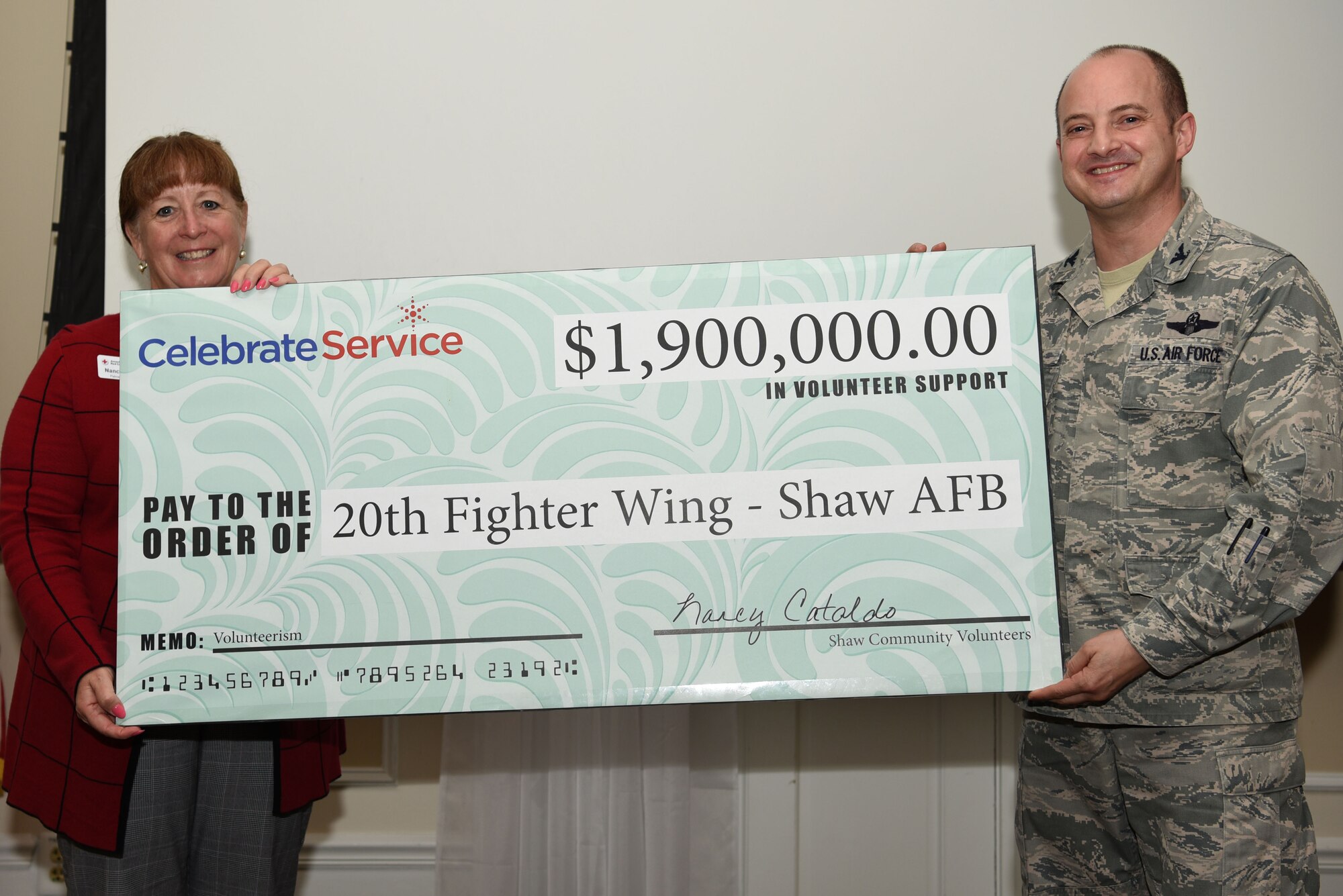 U.S. Air Force Col. John Bosone, 20th Fighter Wing vice commander, right, receives a symbolic check of $1.9 million from Nancy Cataldo, South Carolina Service of Armed Forces & International Services regional director, during an annual volunteer recognition ceremony at Shaw Air Force Base, S.C., April 19, 2018.