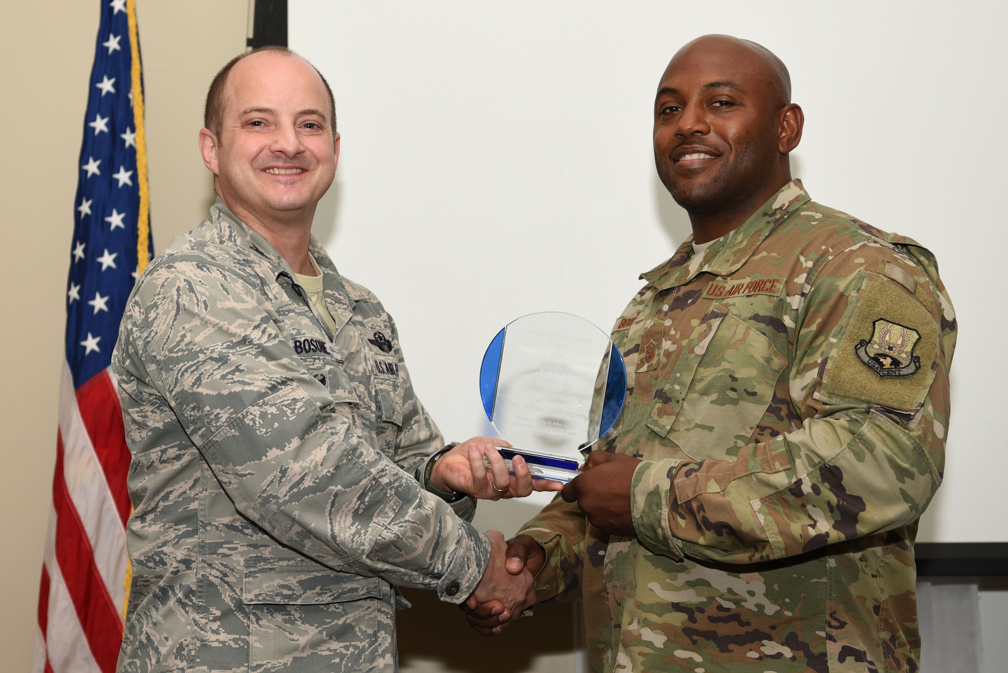 U.S. Air Force Master Sgt. Andre Booker, 51st Intelligence Squadron first sergeant, right, accepts the Volunteer Excellence Award from Col. John Bosone, 20th Fighter Wing vice commander, on behalf of Whitney Armstrong, key spouse, during an annual volunteer recognition ceremony at Shaw Air Force Base, S.C., April 19, 2018.