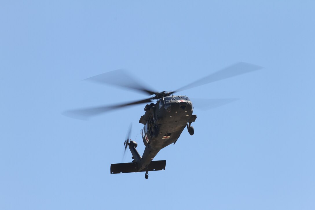 A helicopter flies through blue sky.