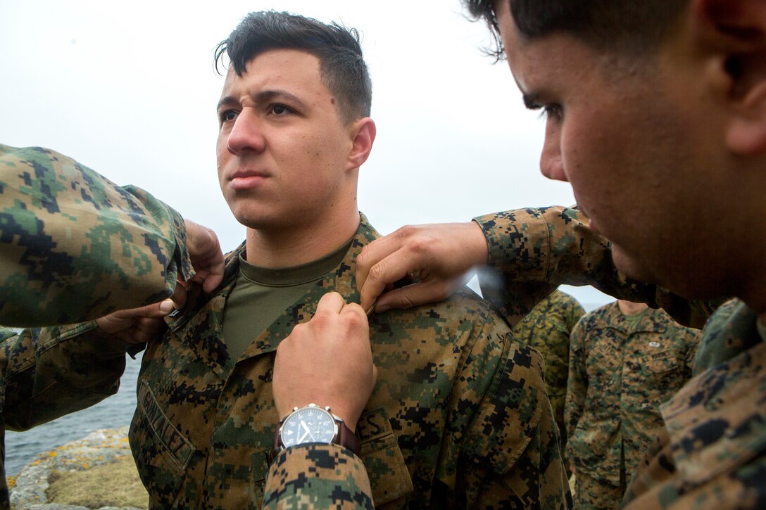 Cpl. Esteban Gonzalez (left), a radio operator with 4th Air Naval Gunfire Liaison Company, Force Headquarters Group, stands at attention during his promotion while Cpl. David Rodriguez (right), a forward observer with 4th ANGLICO, FHG, attaches new corporal chevrons to his blouse, in Cape Wrath, Scotland, April 23, 2018.