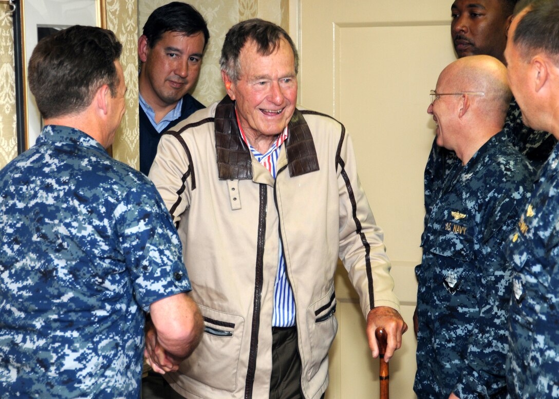 Former President George H.W. Bush shakes hands with crew members aboard the aircraft carrier that bears his name,