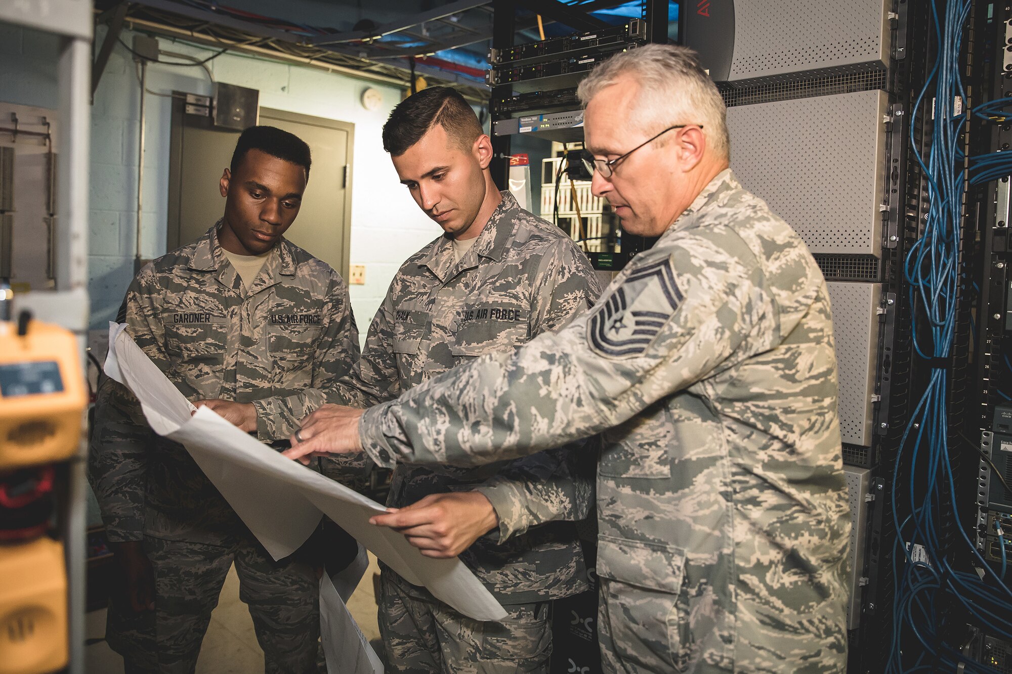U.S. Air Force Senior Master Sgt. Mark Buchanan, right, superintendent, Staff Sgt. Charles Chalk, center, cable and antenna technician, and Staff Sgt. Wilson Gardner, airfield systems technician, from the 202d Engineering Installation Squadron (EIS), Georgia Air National Guard (ANG), review technical drawings at Muñiz ANG Base in San Juan, Puerto Rico, April 19, 2018. The 202d EIS deployed to the Puerto Rico Air National Guard’s 156th Airlift Wing as part of the Hurricane Irma and Maria recovery efforts to spearhead a large-scale project relocating communications systems cabling and equipment to a new hardened facility.