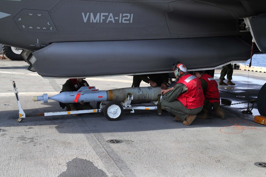 Marines load a GBU-12 Paveway II laser-guided bomb onto an aircraft.