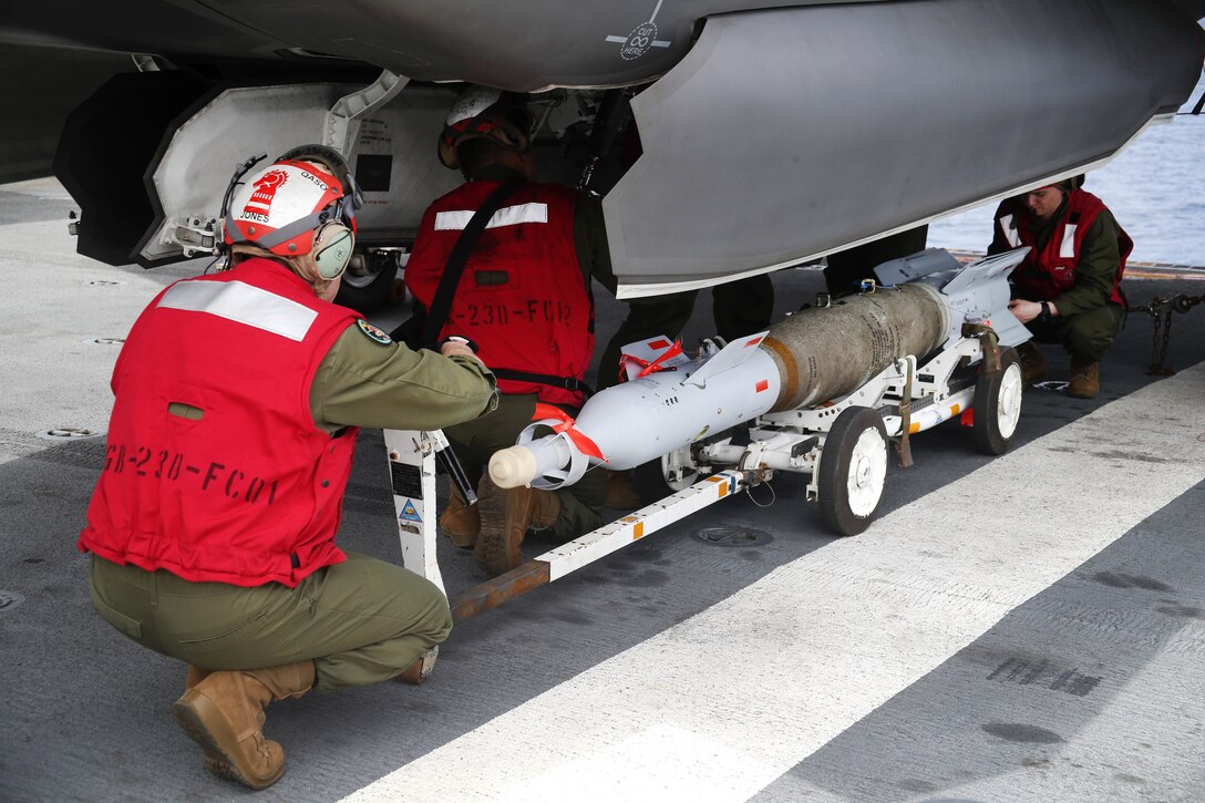 Marines load a GBU-12 Paveway II laser-guided bomb onto an aircraft.