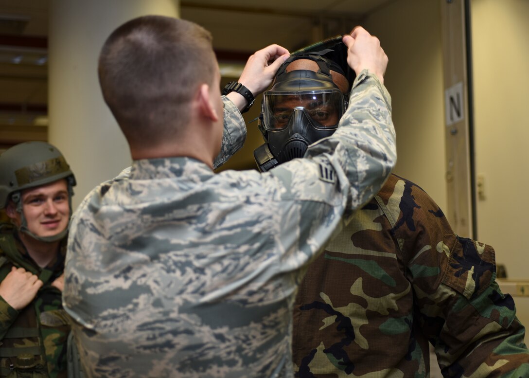 U.S. Air Force Senior Airman Brian Tripp, 51st Civil Engineer Squadron emergency management journeyman, helps National Basketball Association Legend Richard “Rip” Hamilton, put on mission oriented protective posture gear during a USO tour at Osan Air Base, Republic of Korea, April 23, 2018.