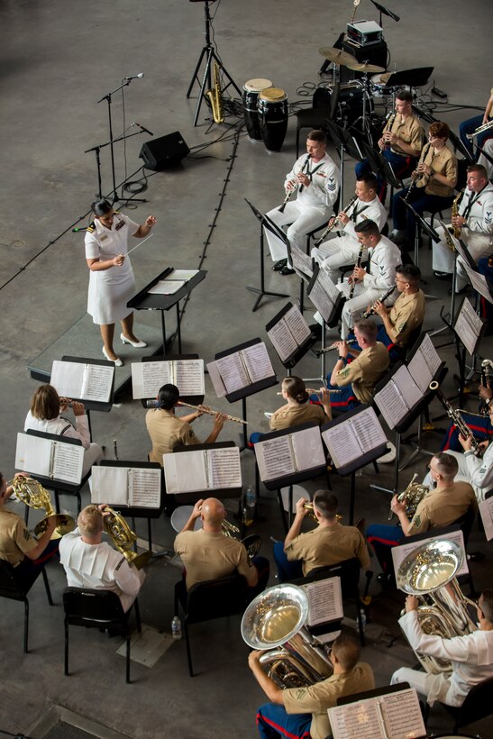 Luslaida Barbosa (left), director of Navy Band Southeast, conducts the Marines with Marine Corps Band New Orleans and the sailors from Navy Band Southeast out of Jacksonville, Florida, perform at the World War II Museum for Navy week in New Orleans, April 21, 2018.