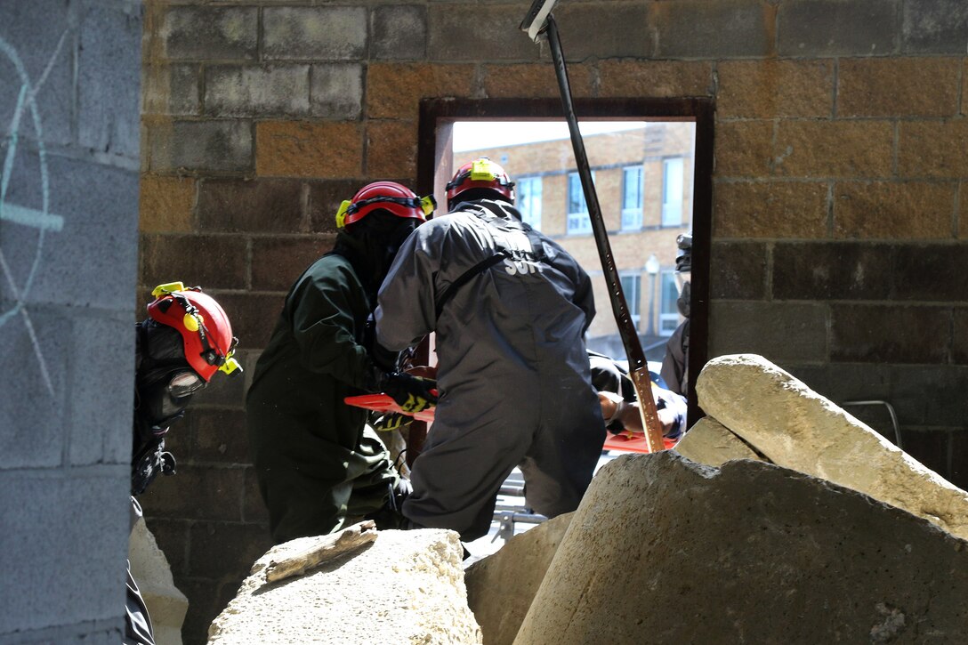 Soldiers move a mock casualty on a stretcher from a building.