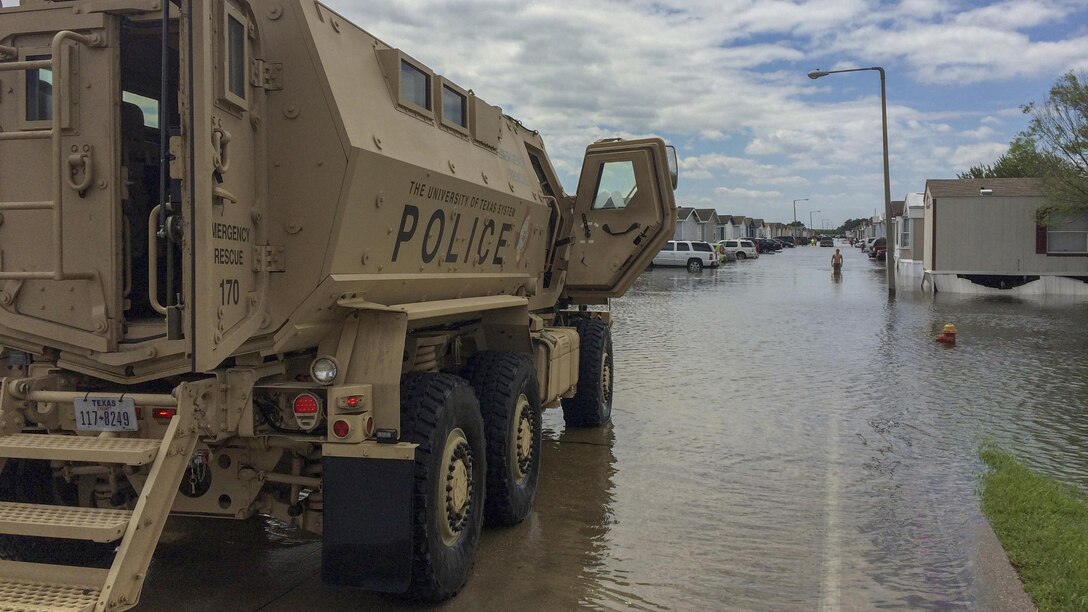 An armored vehicle sits at one end of a flooded street