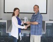 John Lamb, biologist at Arnold Air Force Base, displays his 2018 National Military Fish and Wildlife Association National Resources Conservation Management Award for Model Programs and Projects with Shannon Allen, Chief, National Environmental Policy Act, Natural and Cultural Resources, as she congratulates him. This award category recognizes resource managers who further natural resource management on military installations in support of the military mission through developing programs or projects which can serve as models for conservation on military installations. (U.S. Air Force photo/Deidre Ortiz)