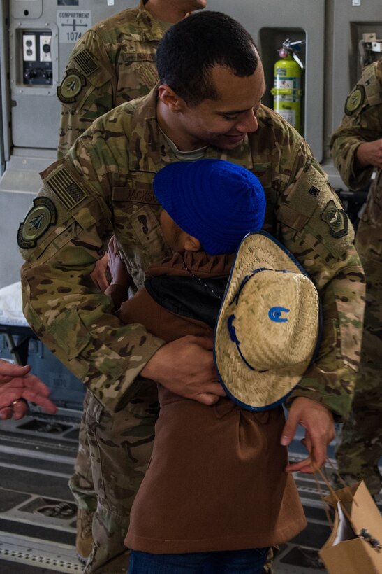 A child hugs a soldier.