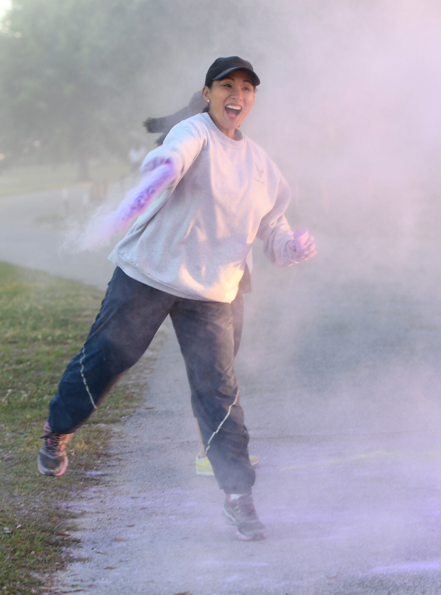 U.S. Air Force Chief Master Sgt. MaryAnn Navarro-Davis, 81st Mission Support Group superintendent, tosses purple powder on runners during the Air Force Assistance Fund Color Run at Keesler Air Force Base, Mississippi, April 20, 2018. The AFAF raises funds for charitable affiliates that provide support to Air Force families in need. (U.S. Air Force photo by Kemberly Groue)