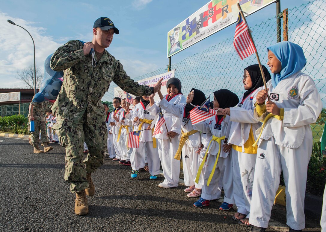 A sailor greets students during a community engagement.