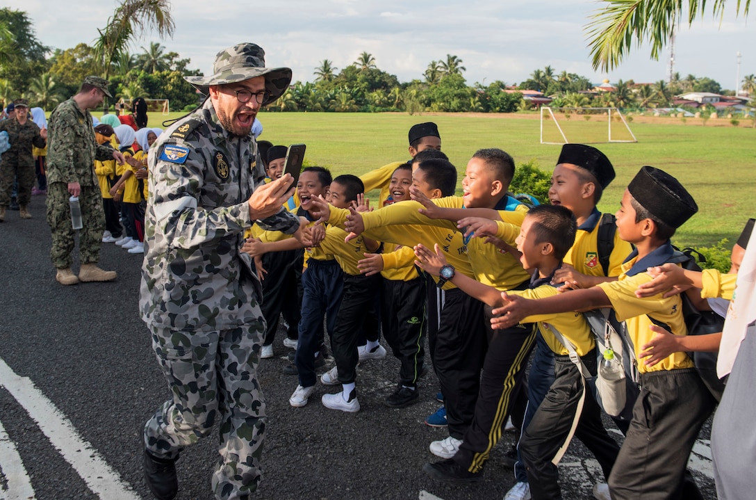 A Royal Australian Navy seaman greets students.