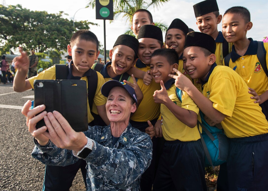 An officer takes a selfie with the students of the school.