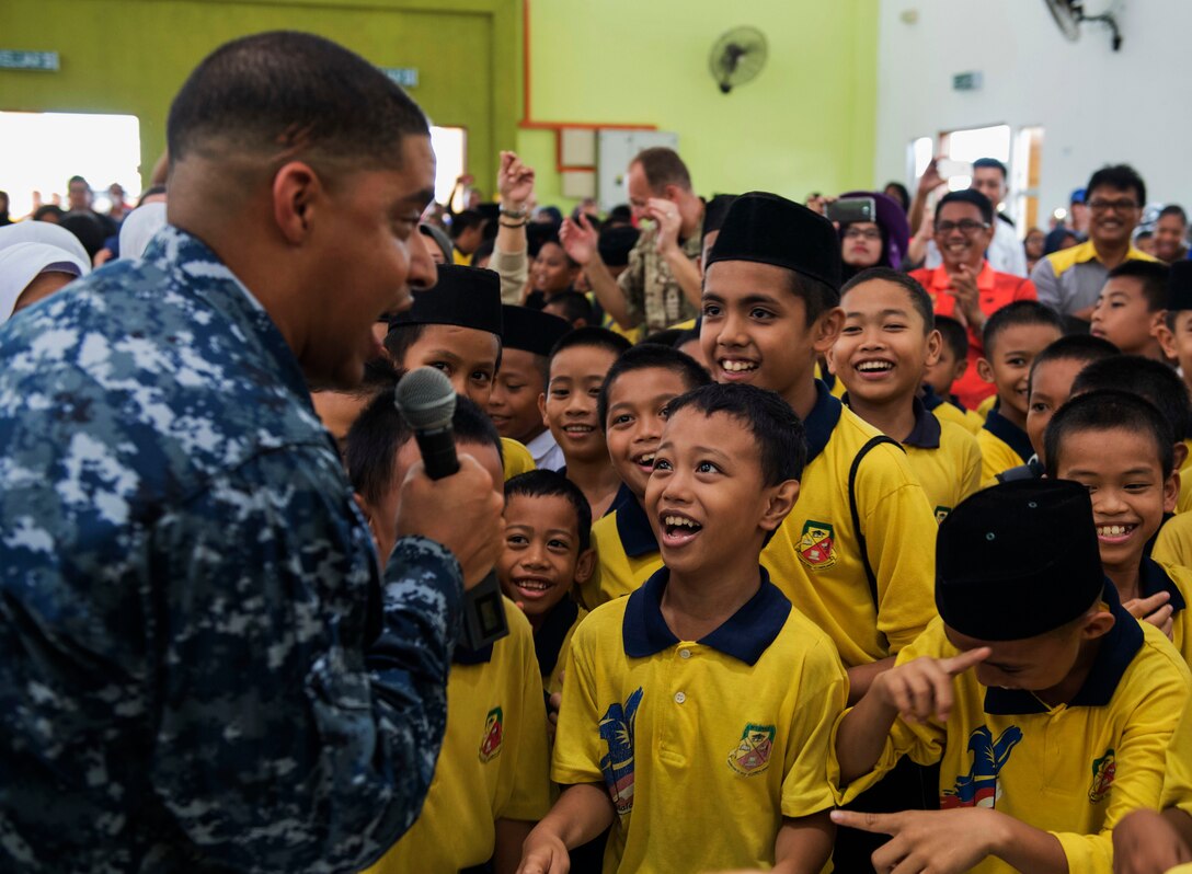A sailor sings to students during a performance by the Pacific Fleet Deep Six Brass Band.