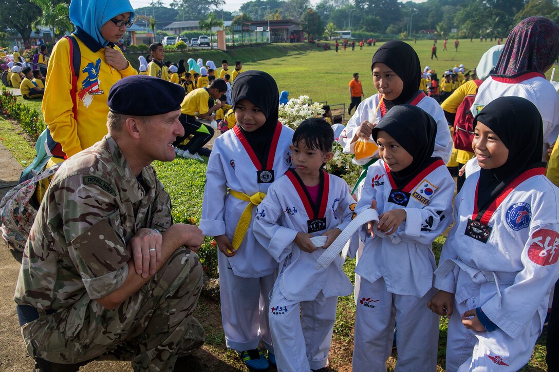 A Royal Navy officer speaks to taekwondo students at the school.
