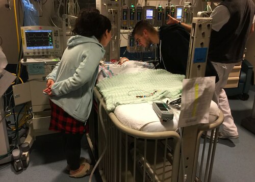 Ashley Mockovciak, Team Shaw spouse, left, and Tech. Sgt. Ben Mockovciak, 372nd Training Squadron Detachment 202 F-16 tactical aircraft maintenance instructor, lean over their son Noah’s bed at a hospital at Charleston, S.C., circa February 2017.