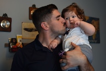 U.S. Air Force Tech. Sgt. Ben Mockovciak, 372nd Training Squadron Detachment 202 F-16 tactical aircraft maintenance instructor, gives his son, Noah Mockovciak, a kiss on the cheek while in their home at Columbia, S.C., March 15, 2018.