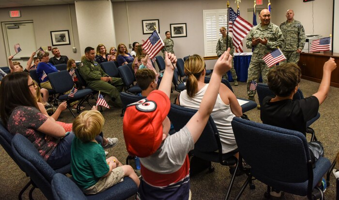 Attendees of the Airman and Family Readiness Center’s “Little Heroes” ceremony wave flags as Col. Jimmy Canlas, 437th Airlift Wing commander, delivers a speech April 18, 2018, at Joint Base Charleston, S.C.
