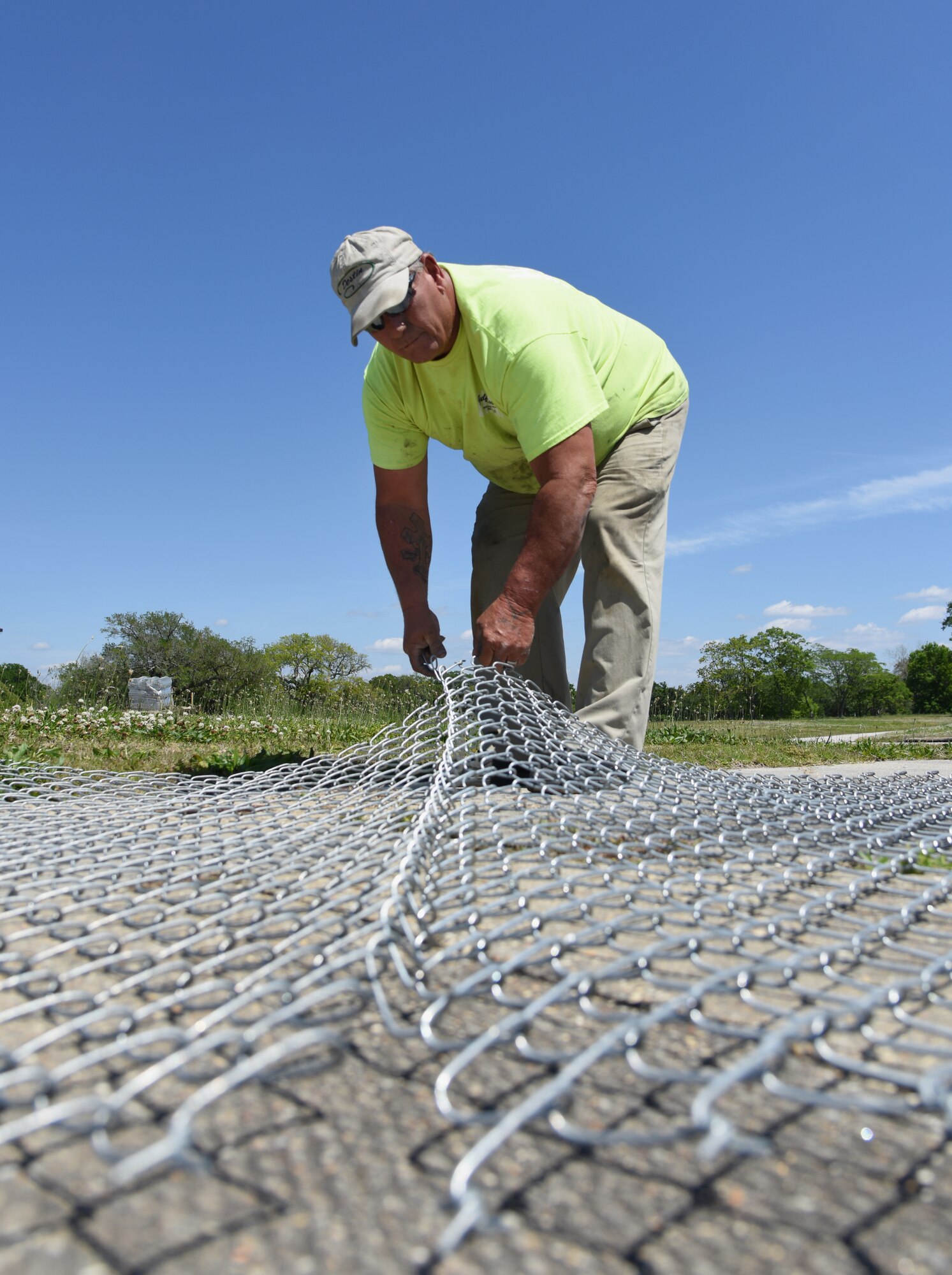 Donald Gonzalez, Gulf Coast Fence Company superintendent, assembles fencing in the open grass area near the commissary at Keesler Air Force Base, Mississippi, April 10, 2018. The fence will serve as a perimeter around the site of the new Division Street Gate entrance construction. The two-year project includes an expanded and enhanced boulevard along Division St. from I-110 to Forrest Ave. (U.S. Air Force photo by Kemberly Groue)