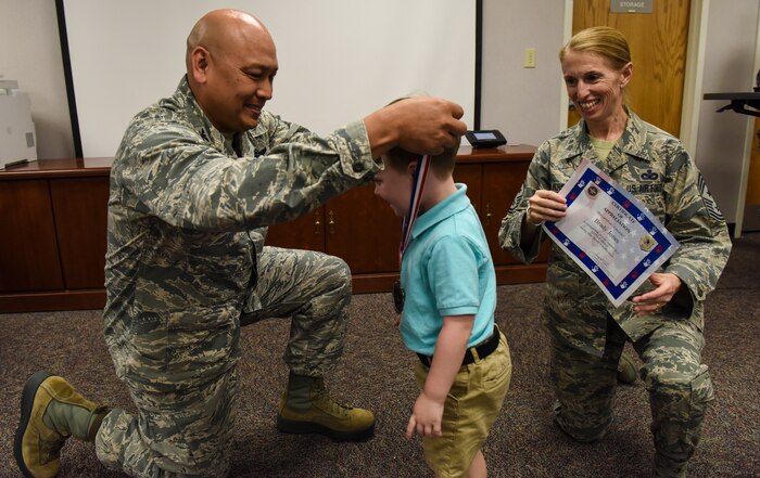 Col. Jimmy Canlas, left, 437th Airlift Wing commander, places a medal on Brady Jones, center, recognized ‘Little Hero’, while Chief Master Sgt. Jennifer Kersey, right, 437th AW command chief holds a certificate April 18, 2018, at Joint Base Charleston, S.C.