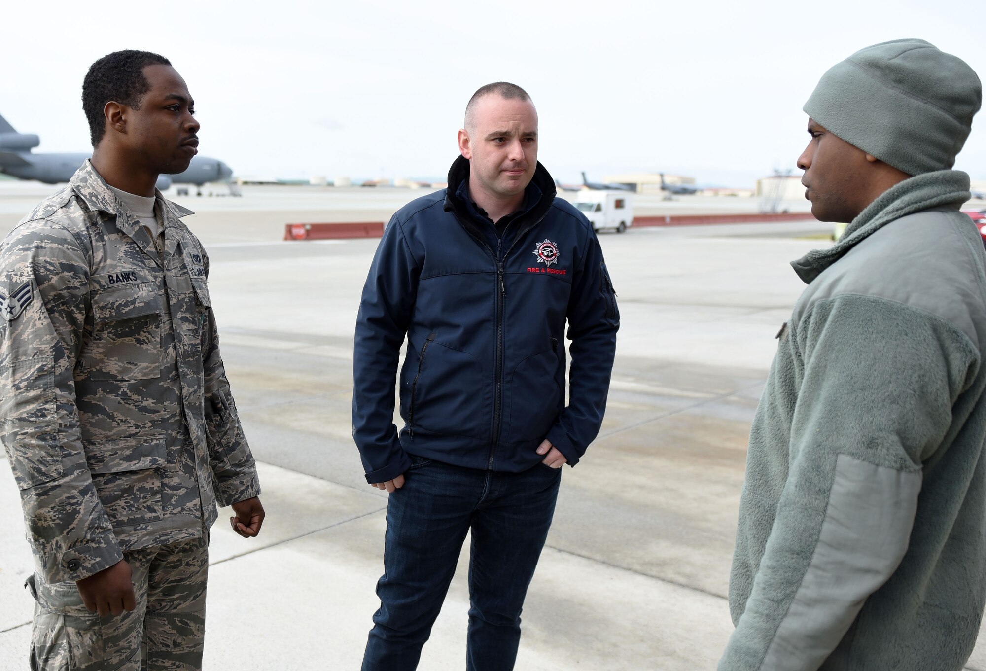 Aaron McAuley, center, a Belfast International Airport Rescue and Firefighting Service crew commander, stands with Senior Airmen Shannon Banks, left, and Danny Thomas, right, both 60th Civil Engineer Squadron firefighters during a meet and greet session April 11 at Travis Air Force Base, Calif. In addition to empowering each other through spirituality, Firefighters for Christ also encourages the exchanging of ideas and methods so as to keep the skills of each participating firehouse sharp and efficient. (U.S. Air Force photo by Airman 1st Class Christian Conrad)