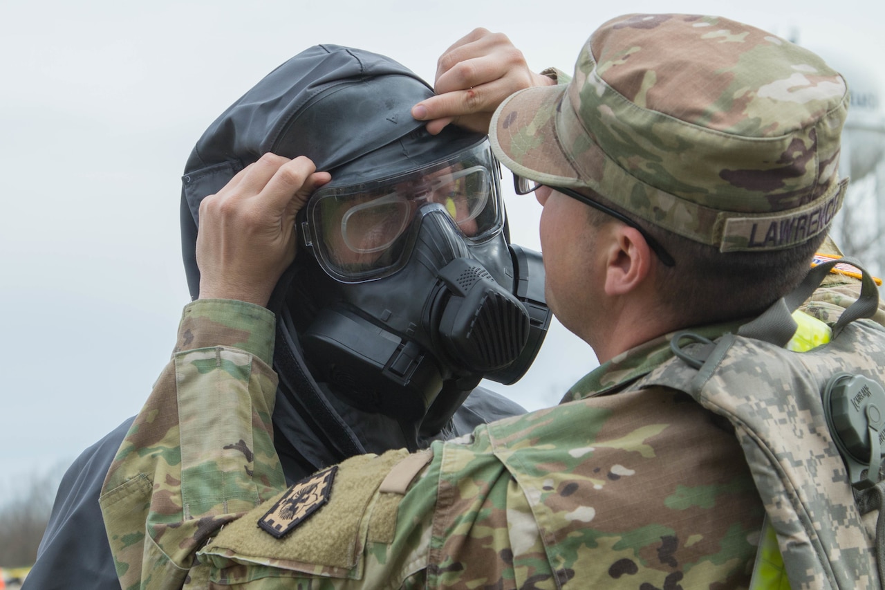 Army Spc. Logan Lawrence adjusts the hazardous materials suit of Army Pvt. Brandon Cormeir, both from 3rd platoon, 22nd Engineer Clearance Company, before Cormeir enters the exercise “hot zone” during the Guardian Response 18 exercise at Muscatatuck Urban Training Center, Ind.