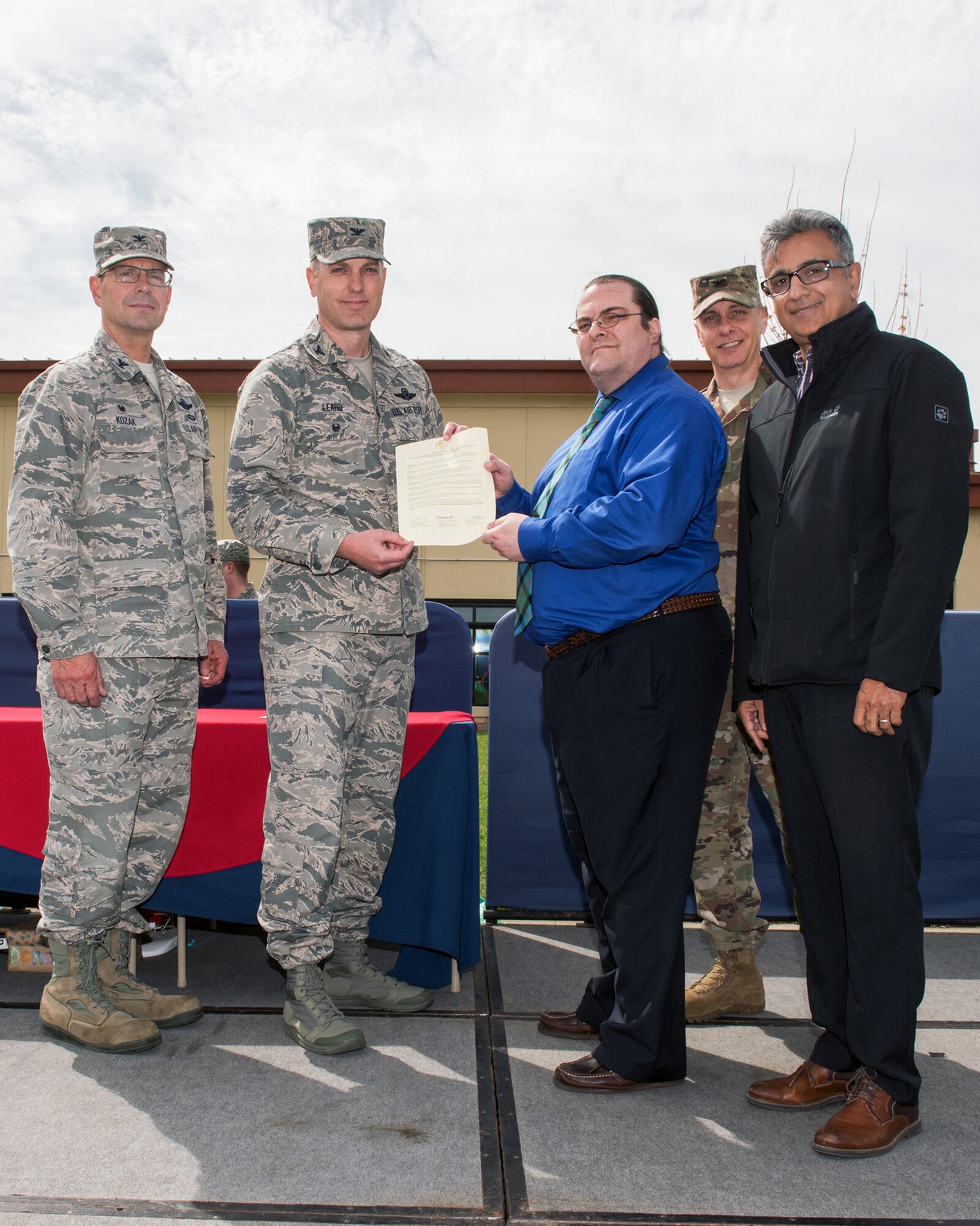 U.S. Air Force Col. Raymond Kozak, left, 349th Air Mobility Wing commander and Col. Matthew Leard, second to left, 60th Air Mobility Wing vice commander, present the signed proclamation during the Family Fun Fest at Travis Air Force Base, Calif., April 11, 2018