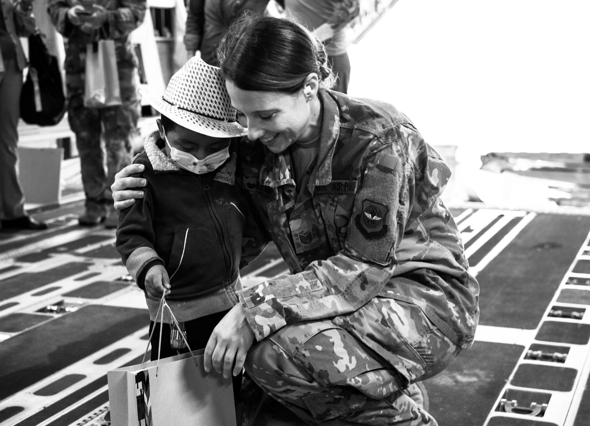 U.S. Air Force Tech. Sgt. Traci Keller, 60th Air Mobility Wing Public Affairs broadcast journalist, shares a moment with a local child after covering the delivery of emergency response vehicles through the Denton Program at La Aurora International Airport, Guatemala City, Guatemala, April 20, 2018. The Denton Program is a Department of Defense transportation program that moves humanitarian cargo, donated by U.S. based Non-Governmental Organizations to developing nations to ease human suffering. The emergency vehicles were donated by the Mission of Love Foundation, they are the largest user of the Denton Program, having delivered medical, relief and humanitarian supplies to needy communities throughout the world. (U.S. Air Force Photo by Master Sgt. Joey Swafford)