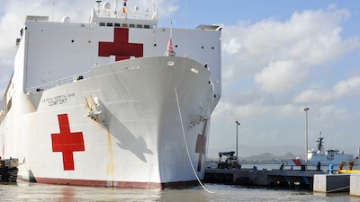 The hospital ship USNS Comfort, white with red crosses, is docked in Puerto Rico