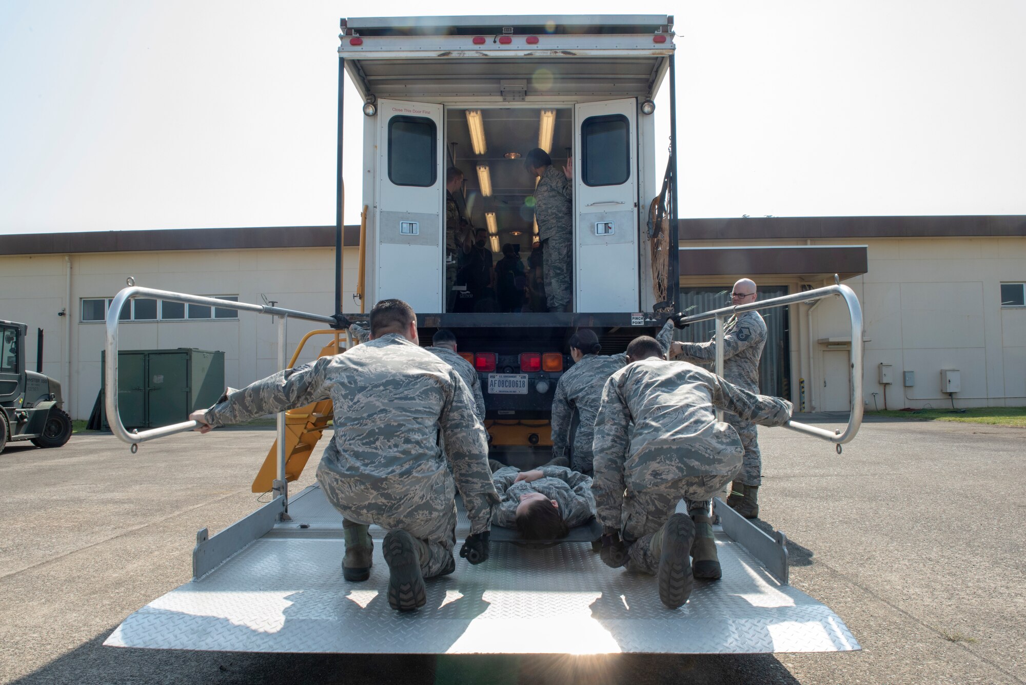 Airmen from the 374th Medical Support Squadron secure a gurney for elevation in demonstration of the En Route Patient Staging System for the members of the USO Spring Tour at Yokota Air Base, Japan, April 22, 2018.