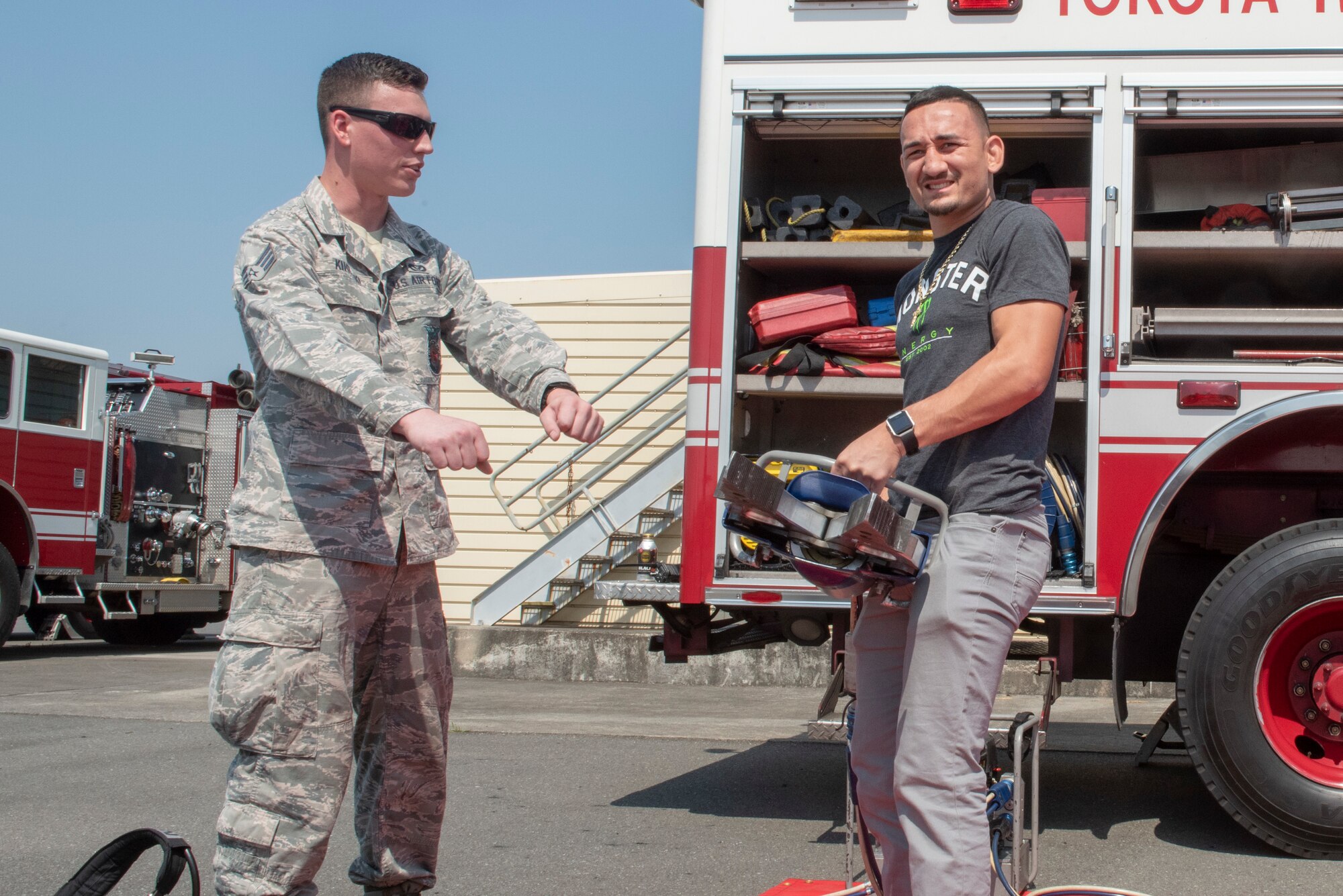 Max Holloway, UFC fighter and undisputed featherweight champion, poses for a photo holding the Jaws of Life during the USO Spring Tour at Yokota Air Base, Japan, April 22, 2018.