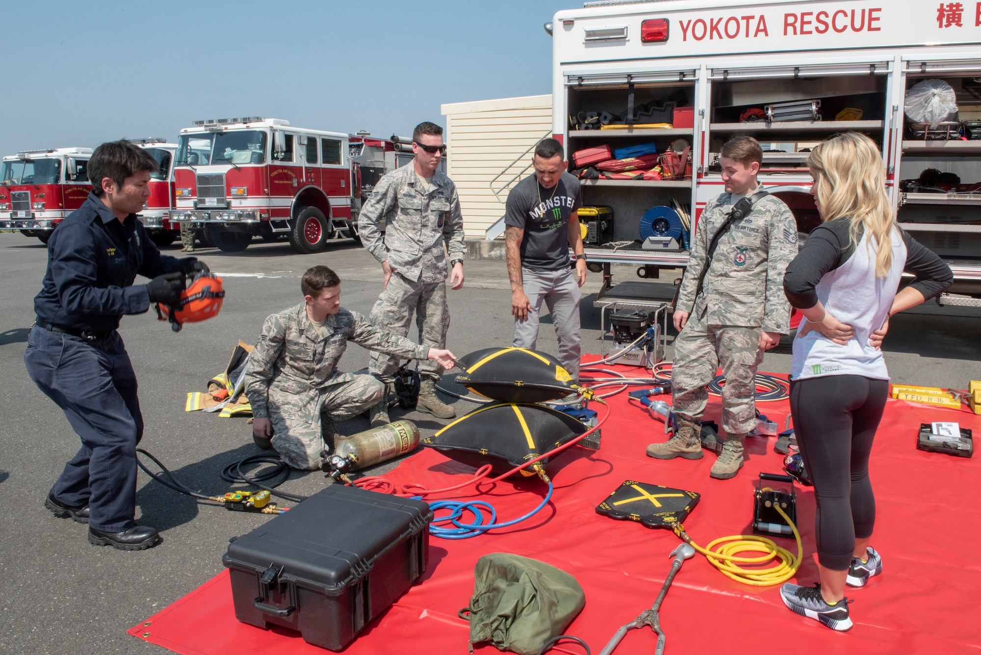 Firefighters from the 374th Civil Engineer Squadron demonstrate the usefulness of high-pressure bags to USO Spring Tour entertainers Max Holloway and Paige VanZant at Yokota Air Base, Japan, April 22, 2018.
