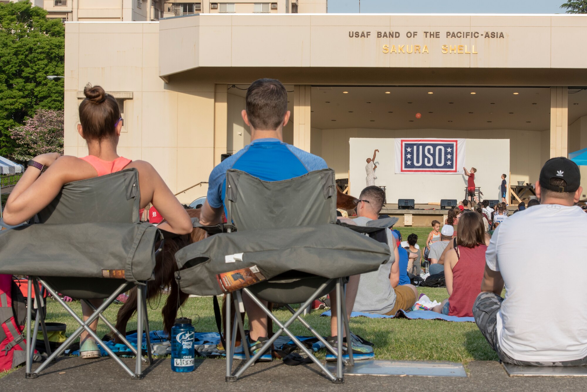 Members of Team Yokota watch on as Richard “Rip” Hamilton, retired NBA player, runs a couple of children from the audience through a set of basketball drills during the USO Spring Tour at Yokota Air Base, Japan, April 22, 2018.