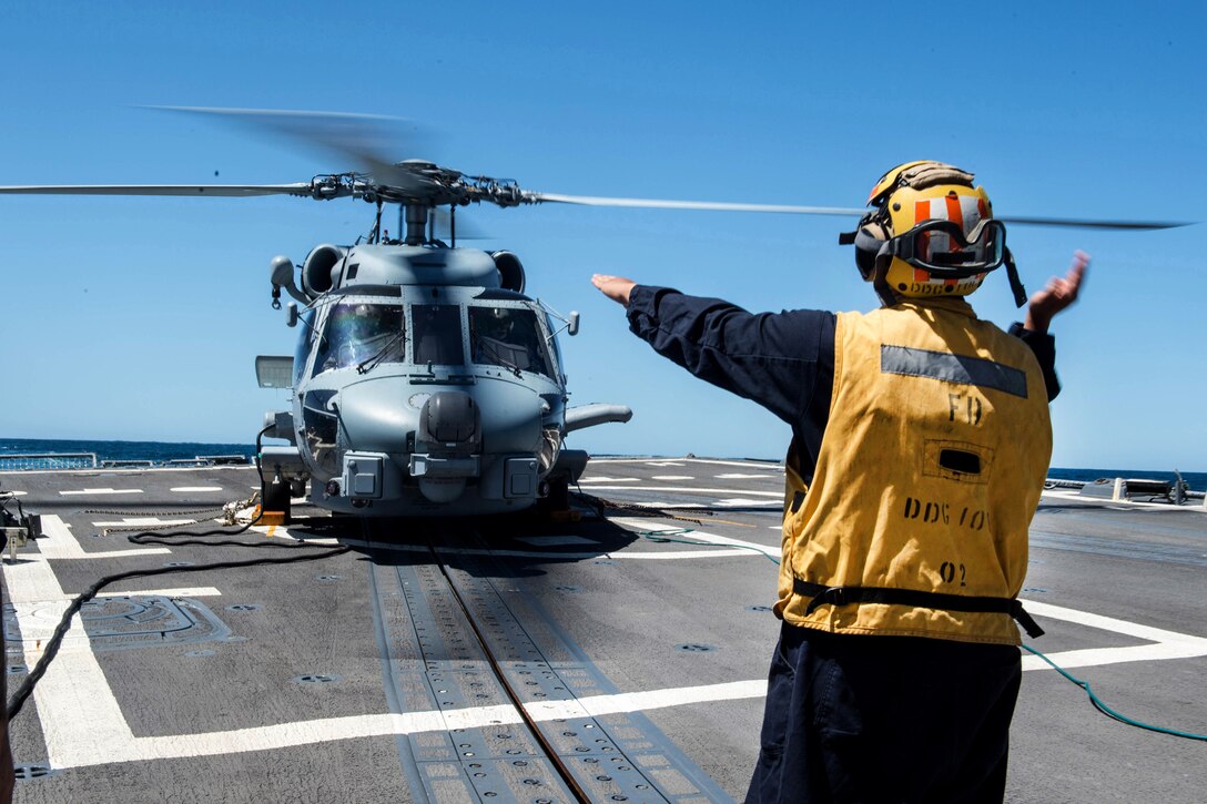 A sailor signals a helicopter.