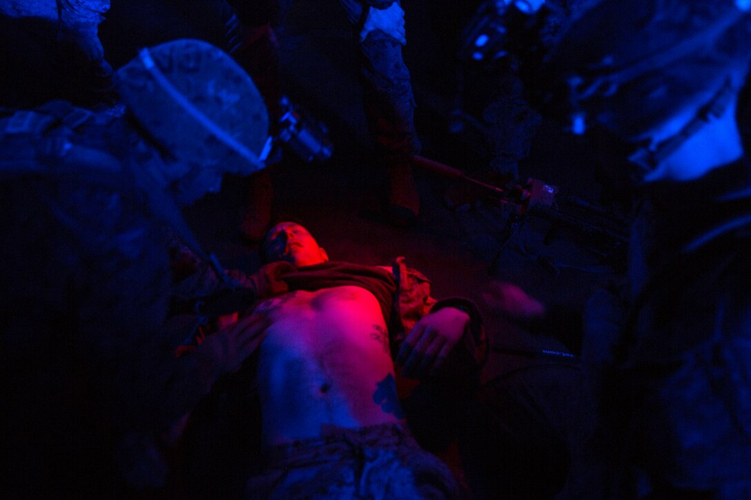 A Norwegian military police car illuminates Marines with Marine Rotational Force-Europe 18.1 assessing a simulated trauma victim inside a hangar during stress inoculation and combat lifesaver training at Vaernes Garnison, Norway, April 20, 2018. Law enforcement Marines and Corpsmen supervising the training blasted participants with sirens and loudspeakers to maximize friction and uncertainty, simulating the fog of war.
