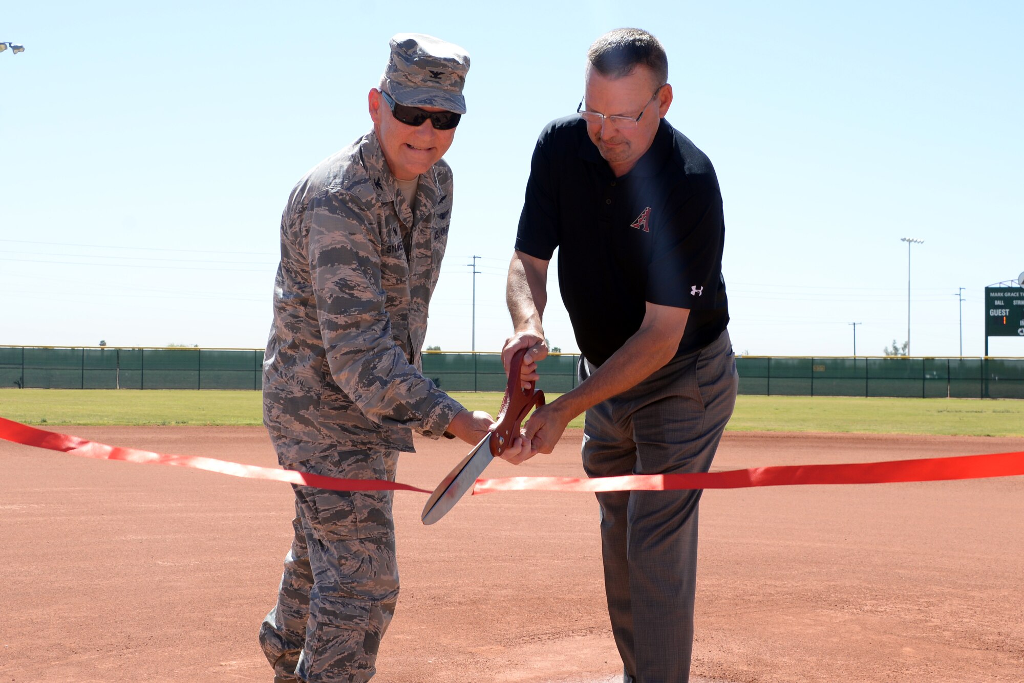 Col. Robert Sylvester, 56th Mission Support Group commander, and Mark Grace, former Arizona Diamondbacks first baseman, cut a ribbon during the scoreboard ribbon cutting ceremony April 23, 2018, at Luke Air Force Base, Ariz. The Diamondbacks, together with Arizona Public Service, presented Luke AFB with a new scoreboard for field number three. (U.S. Air Force photo by Senior Airman Devante Williams)