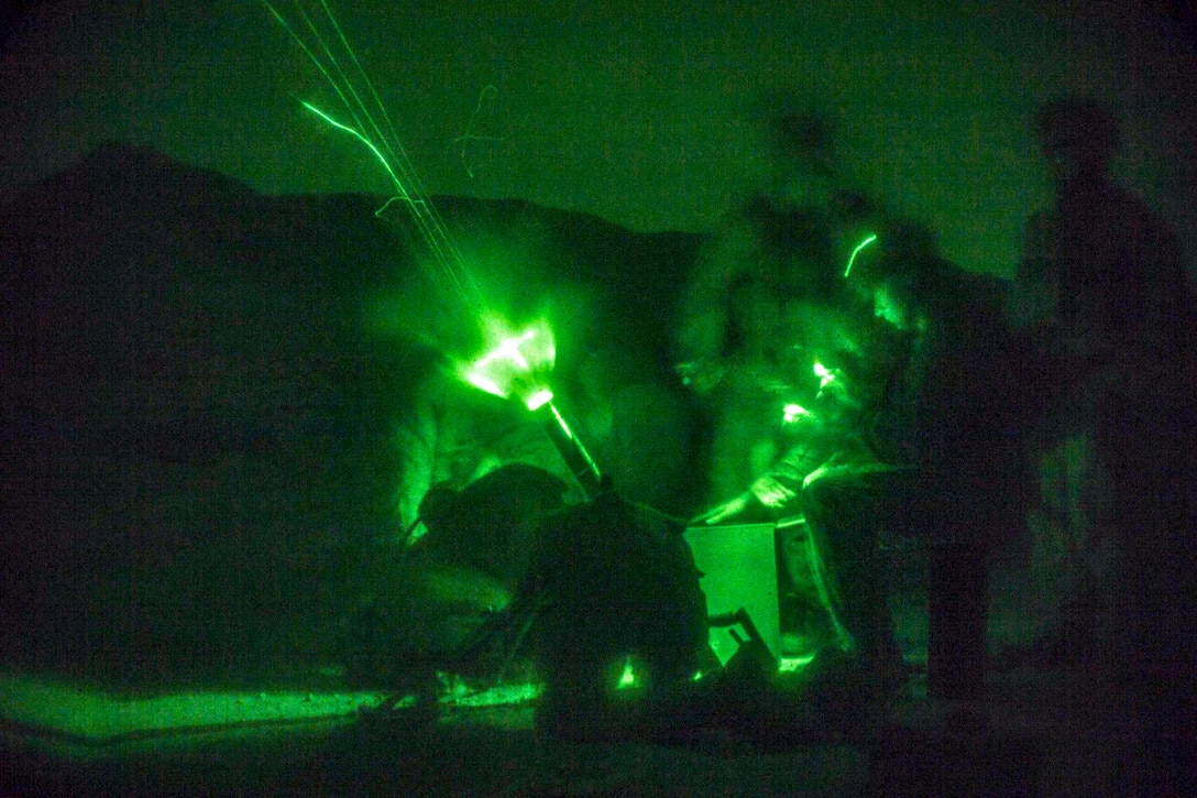 Marines, seen through a night vision device, fire an M224A1 60 mm mortar system.