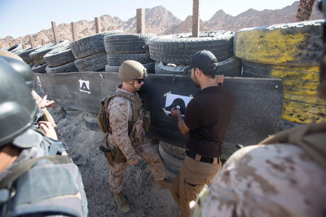 U.S. Marines assigned to the Maritime Raid Force (MRF), 26th Marine Expeditionary Unit (MEU), discusses impact marks on a target with an interpreter assigned to the Royal Jordanian Navy’s 77th Naval Infantry Battalion, during a 25 meter range as part of Eager Lion at King Abdullah Special Operations Training Center, Jordan, April 16, 2018.