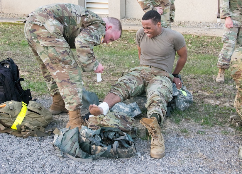 Staff Sgt. Paris Bledsoe, assigned to the 5th Brigade Health Services, 94th Training Division – Force Sustainment, receives help from the medic after turning his ankle during the ruck march portion of the 80th Training Command's 2018 Best Warrior Competition at Fort Knox, Kentucky, April 14, 2018. (U.S. Army Reserve photo by Maj. Addie Leonhardt, 80th Training Command)