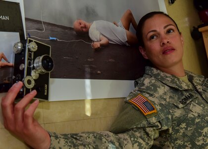 U.S. Army Spc. Wilmarys Roman Rivera, Headquarters and Headquarters Company, 10th Battalion, 7th Transportation Brigade (Expeditionary) tactical power generation specialist, poses next to her photograph at Joint Base Langley-Eustis, Virginia, April 20, 2018. Roman Rivera hiked to the highest peak in Puerto Rico’s El Yunque National Forest to capture herself in her favorite spot. (U.S. Air Force photo by Airman 1st Class Monica Roybal)