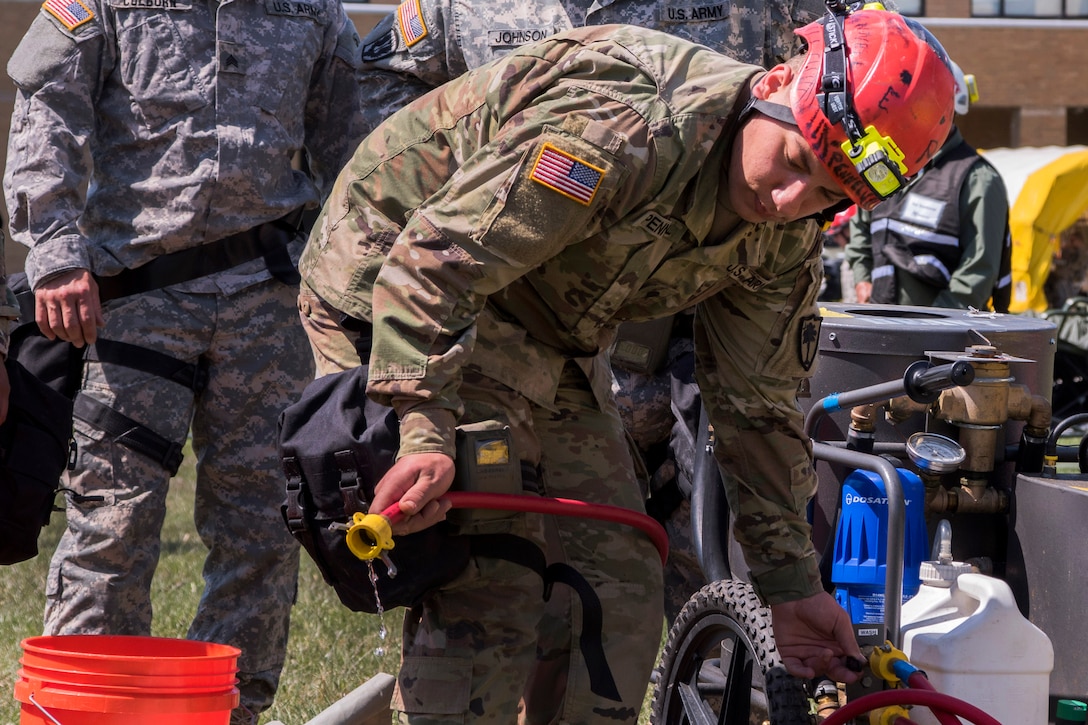 A soldier checks water flow to help begin decontamination.