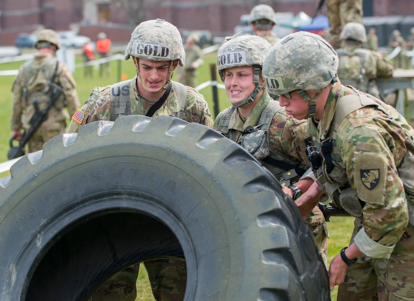 West Point cadets roll a tractor tire during training.