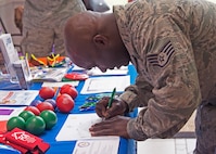 A 919th Special Operations Wing Airman fills out a post card for a  young family member inside the dining facility entrance at Duke Field, Florida, April 7, 2018