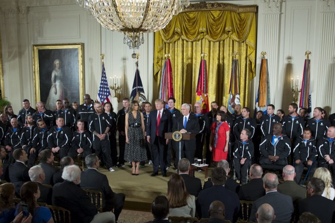 The president and vice president stand on stage with wounded warriors.
