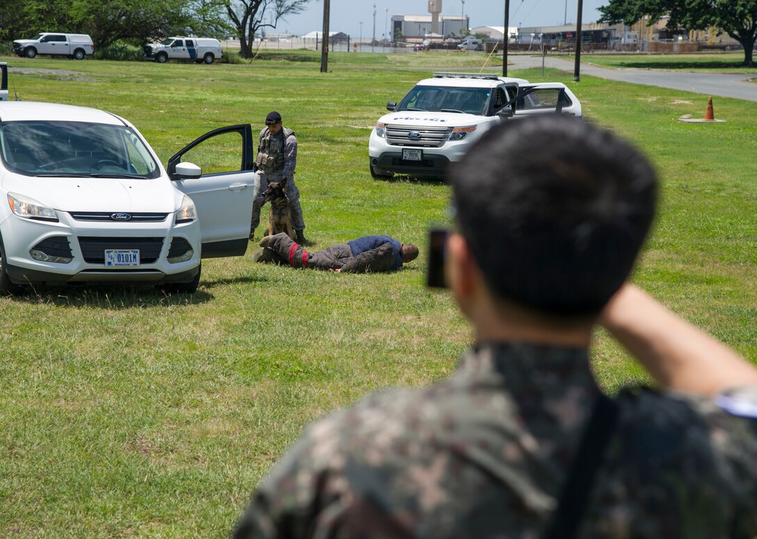 PACIFIC DEFENDER 18-2 participants take photos and video of the Joint Base Security K-9 unit demonstration, Joint Base Pearl Harbor-Hickam, Hawaii, April 10, 2018. PAC DEFENDER 18-2 is a multilateral event intended to enhance strong personal relationships and cooperation with several Asia-Pacific nations.  (U.S. Air Force photo by Tech. Sgt. Heather Redman)
