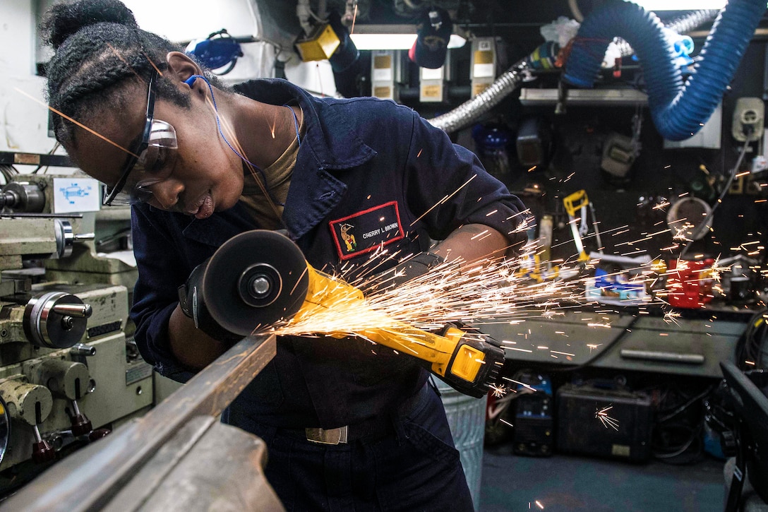 A sailor uses a tool on metal that causes sparks.