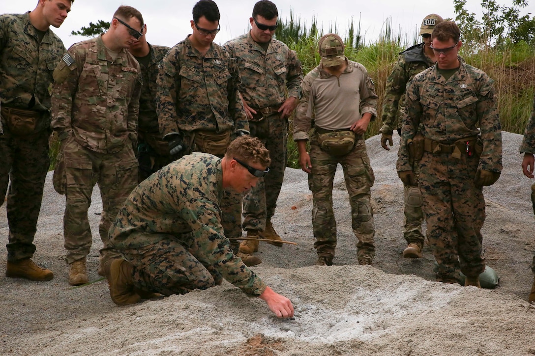 Staff Sgt. Joshua Firth, an explosive ordinance disposal team leader with EOD Company, 9th Engineer Support Battalion, Combat Logistics Regiment 35, points out defining features of an 81mm mortar crater during post-blast analysis training April 25, 2018 at Camp Hansen, Okinawa, Japan. Marines with EOD Company, 9th ESB and Air Force EOD technicians with EOD Unit, 18th Civil Engineers conducted the training to instruct junior technicians on safe disposal of ordnance and examination of ordinance blast craters to determine potential locations for hostile enemy positions. Firth is a native of Seaside, Oregon. (U.S. Marine Corps photo by Sgt. Tiffany Edwards)